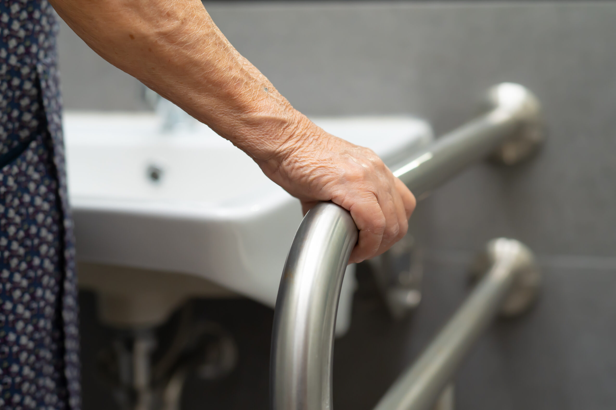Image of an elderly woman holding a grab bar for bath safety